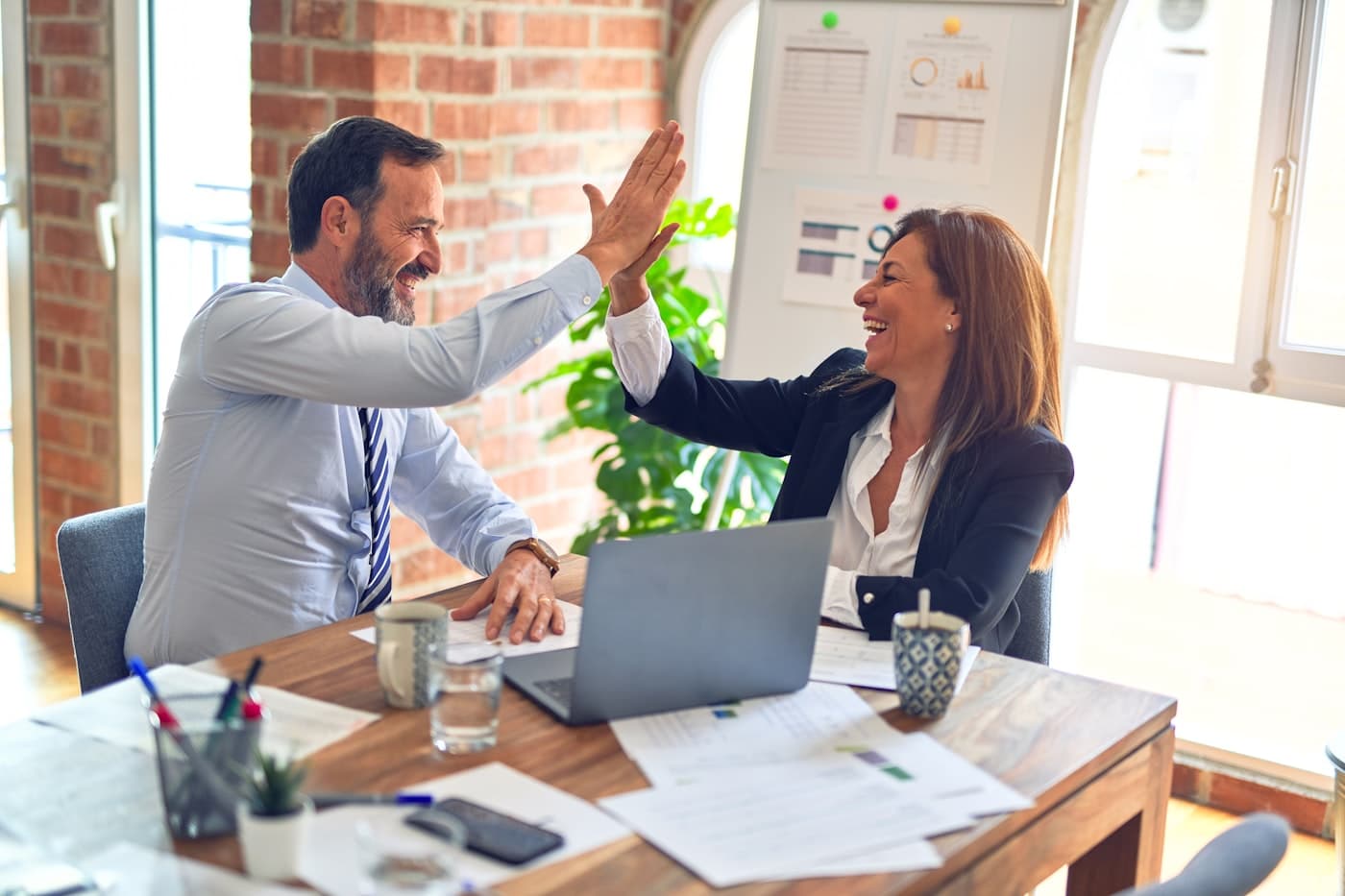 Two bookkeepers celebrating a closed month at their desk